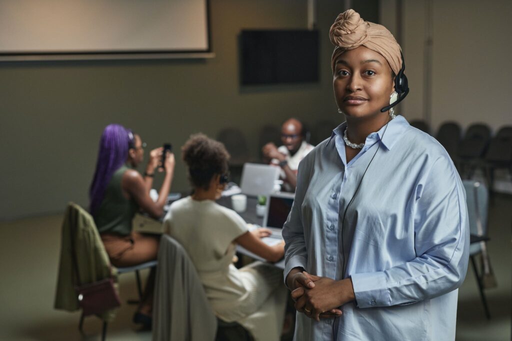 Woman with Headset Standing Beside a Group of People at Work